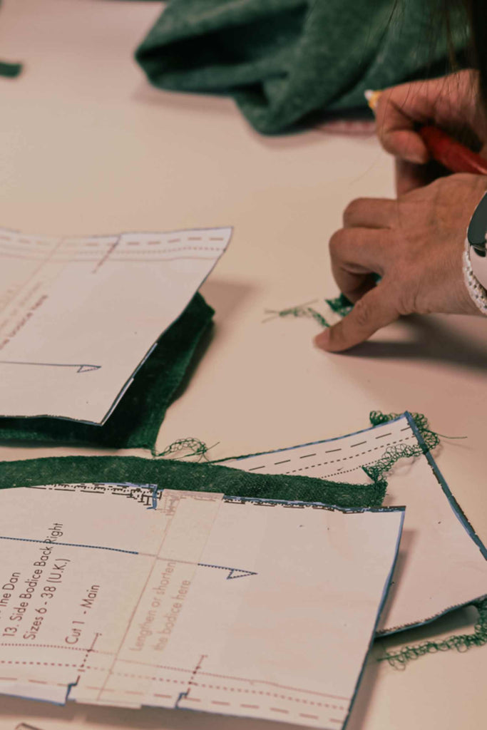 Leim Sewing workshops - jumpsuit sewing workshops - a person working with paper patterns and the green cut out fabric. Sewing pattern adjustments & alterations